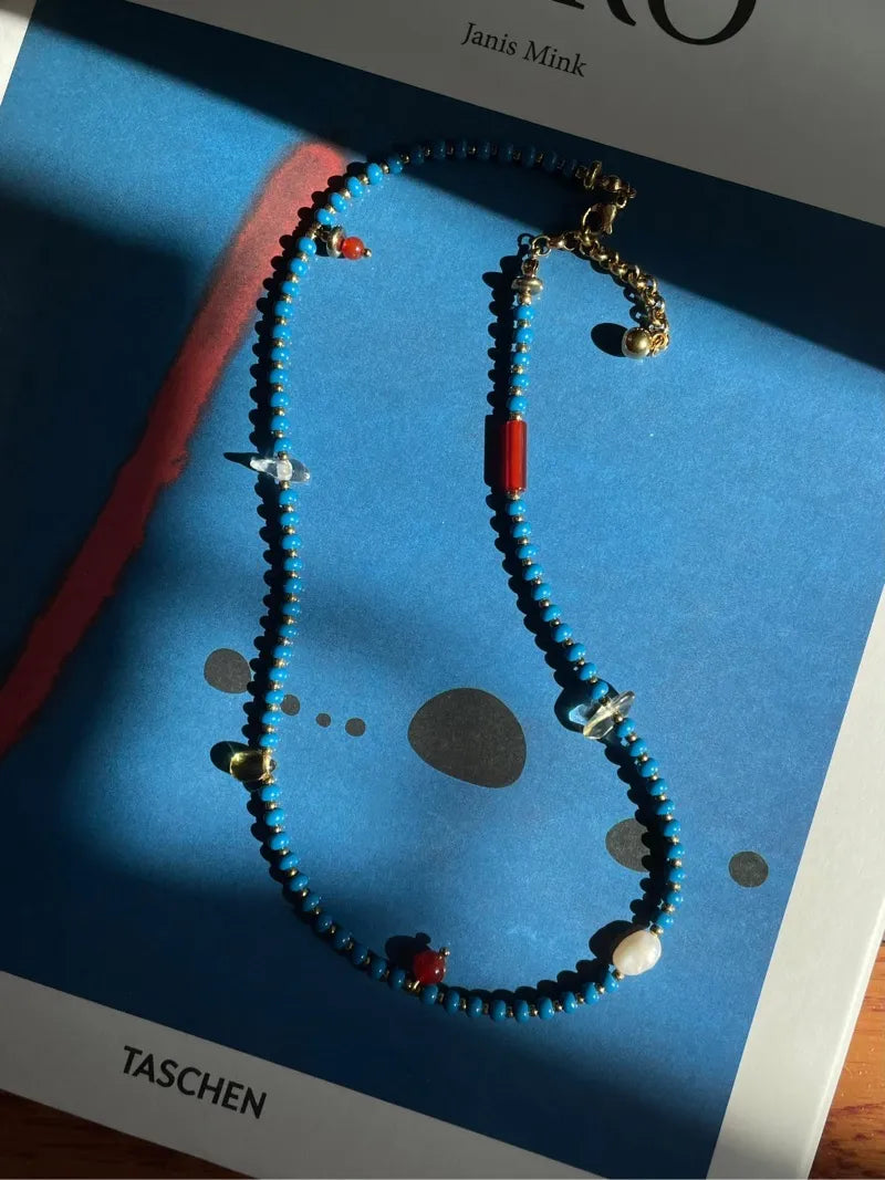 The Blue necklace shown in natural daylight, capturing the true color and beautiful texture of the genuine stones, pearls, and glass beads.