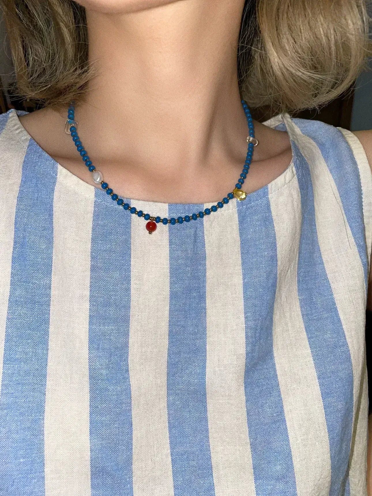 The blue and neutral toned Blue necklace paired with a casual blue stripe tank top for a perfect everyday summer outfit.