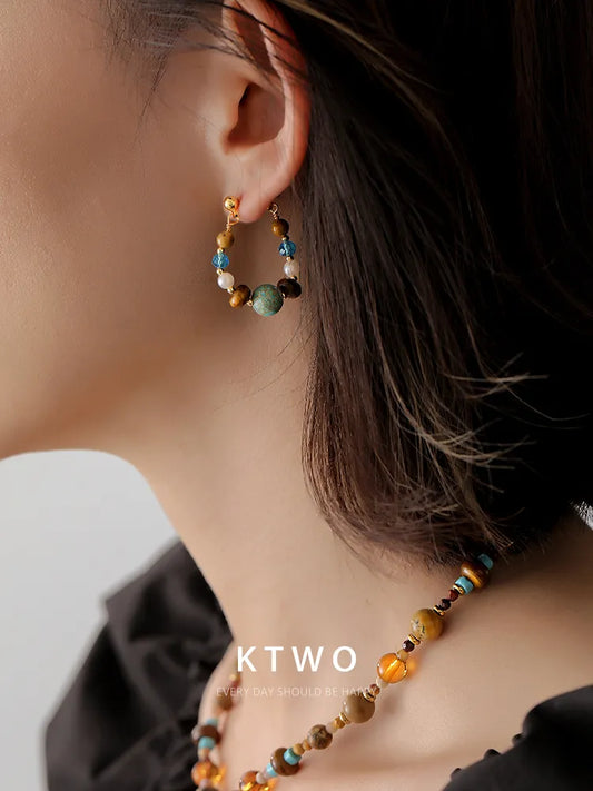 Side view of handmade vintage turquoise and tiger eye stone dangle earrings.