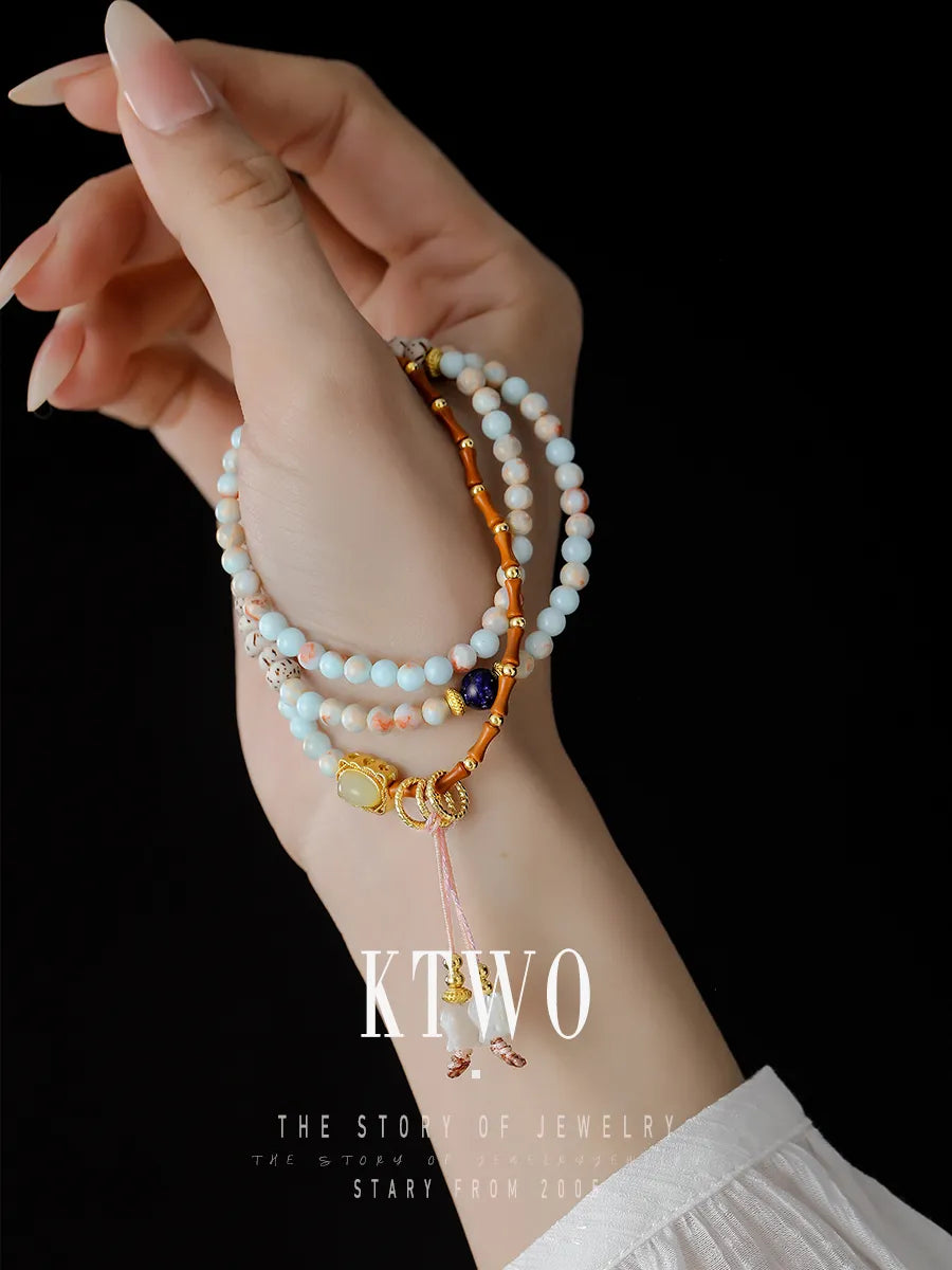 Close-up detail of the versatile bracelet on a model's wrist. Showcases the texture of the lapis lazuli, shell tulip flower, and light blue beads in a stacked style.