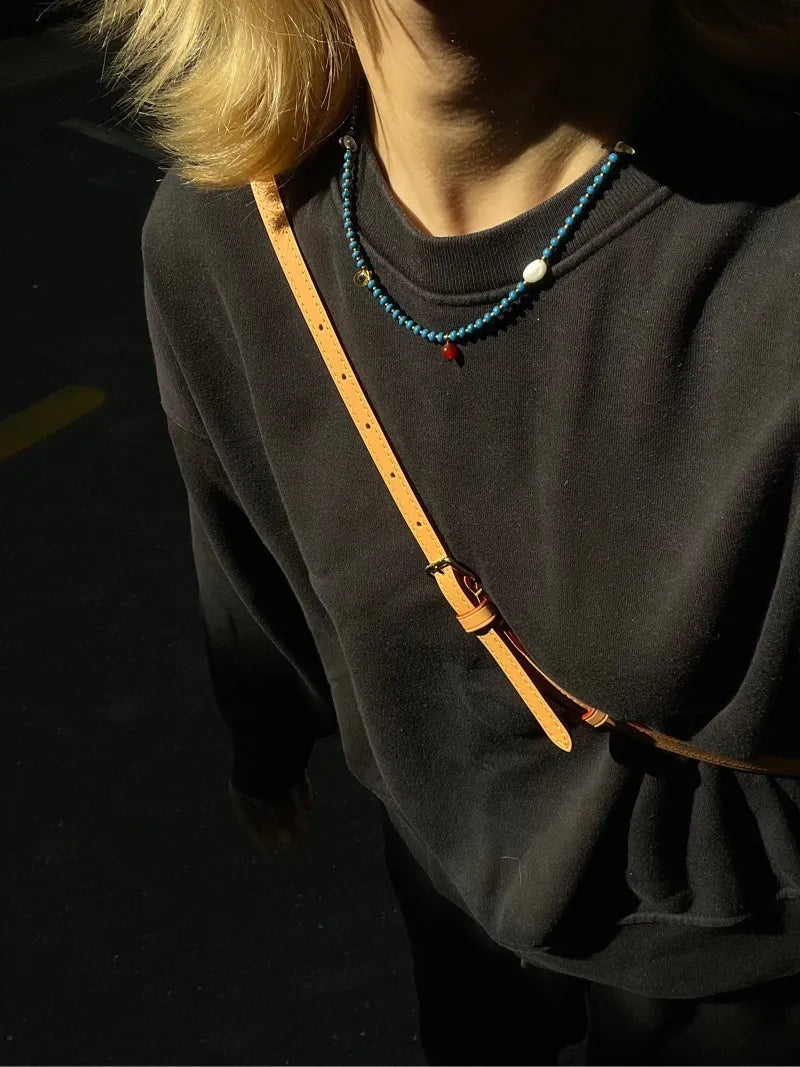 Adding a pop of elegance to a casual outfit, the Blue beaded necklace worn with a comfortable black hoodie.