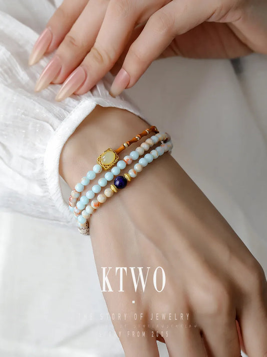 A woman wearing our long convertible bracelet wrapped three times around her wrist for a stylish, layered look. The lapis lazuli and tulip charms create a beautiful bohemian stack.