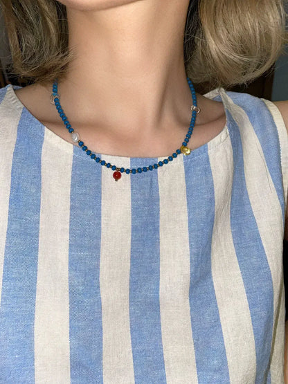 The blue and neutral toned Blue necklace paired with a casual blue stripe tank top for a perfect everyday summer outfit.