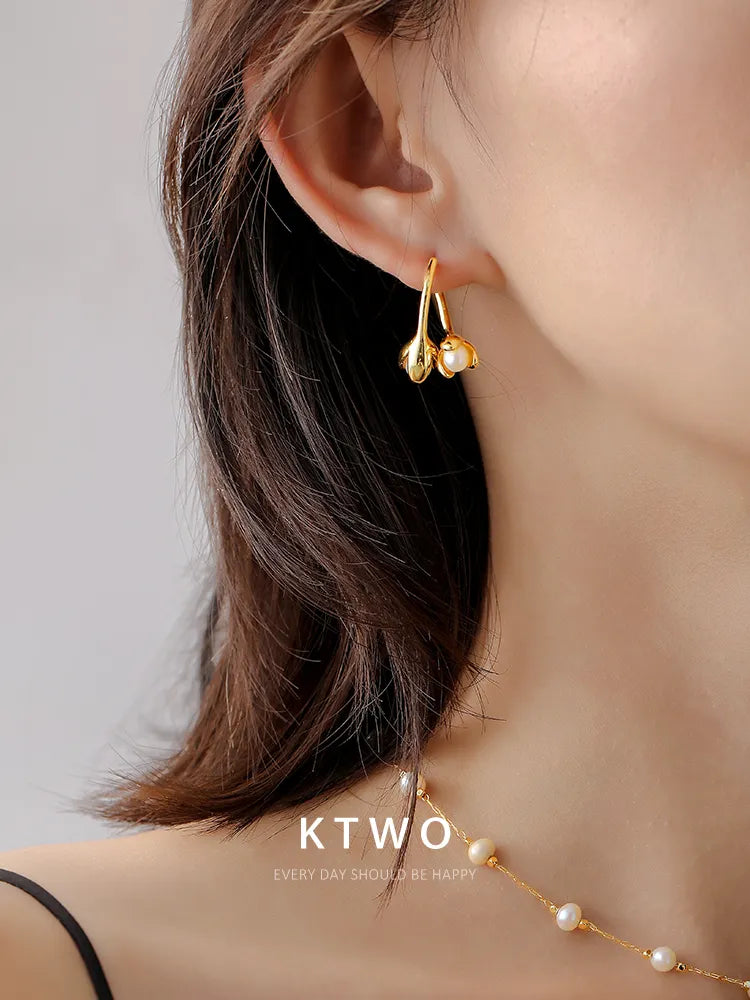 A woman wearing the elegant gold flower and pearl stud earrings.