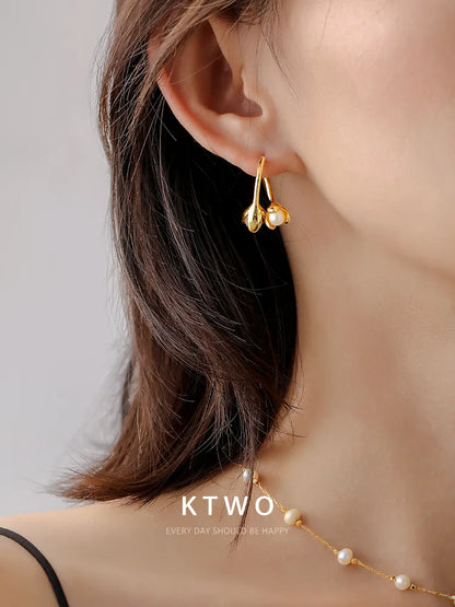A woman wearing the elegant gold flower and pearl stud earrings.