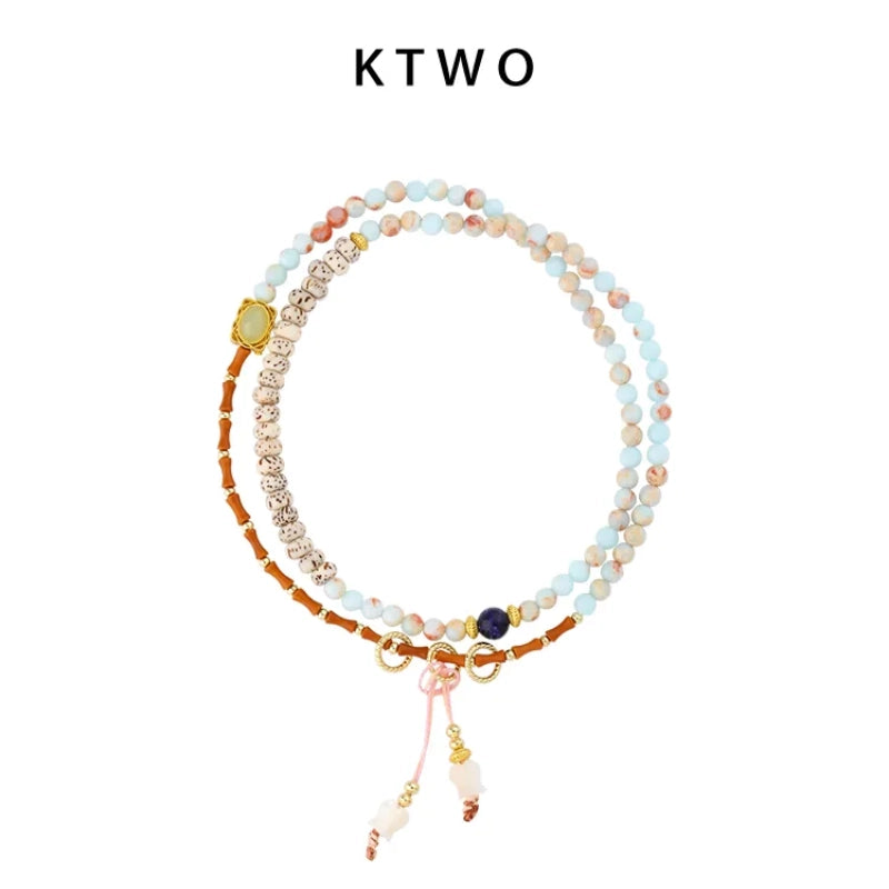 A flat lay of one long, convertible beaded bracelet on a white background. Shows its featuring natural lapis lazuli, shell tulip charms, and light blue beads in a New Chinese style.