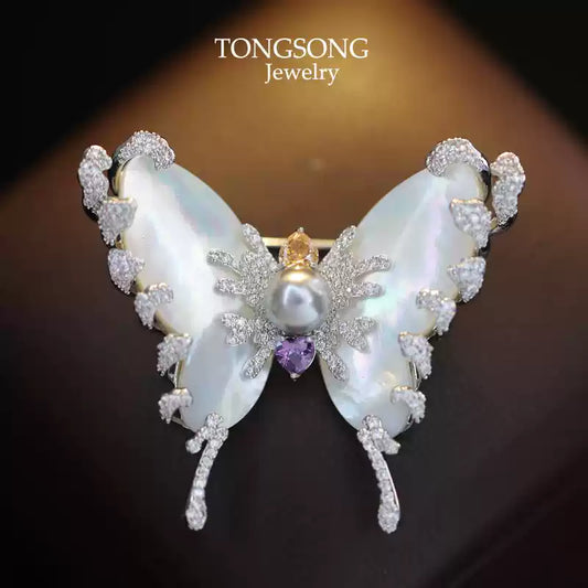 silver tone moth brooch with a baroque gray freshwater pearl body and micro-pavé zircon accents on iridescent shell wings.